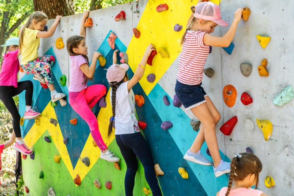 Sechs Mädchen besteigen eine Boulderwand.