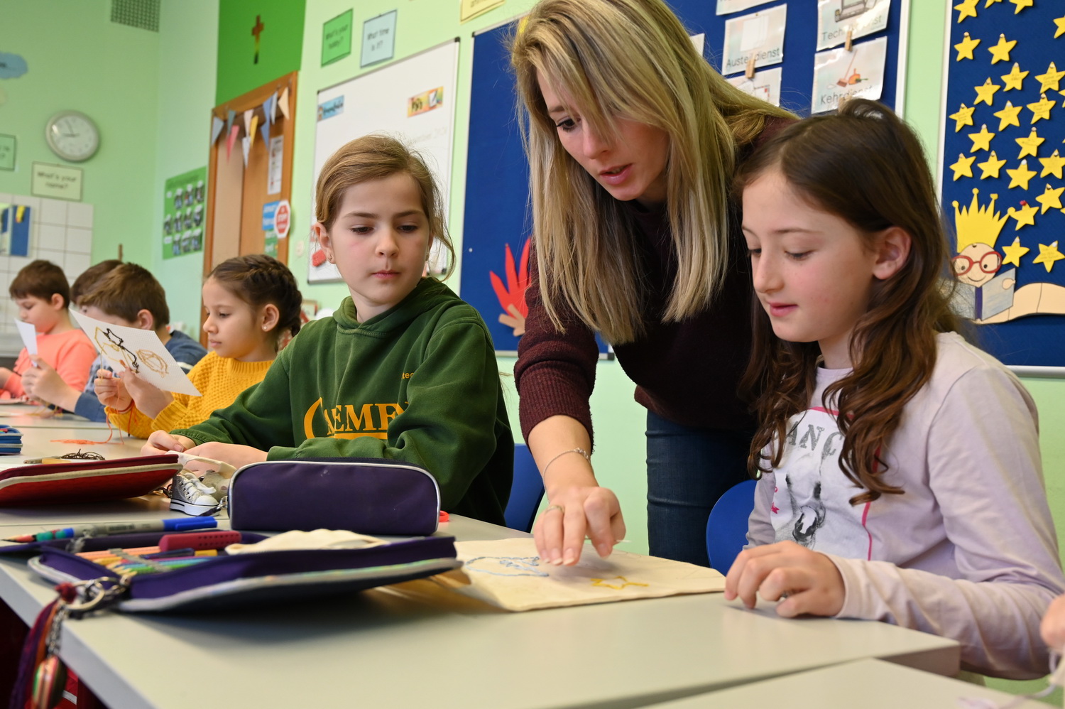 Lehrerin schaut mit Schülerin in Arbeitsheft