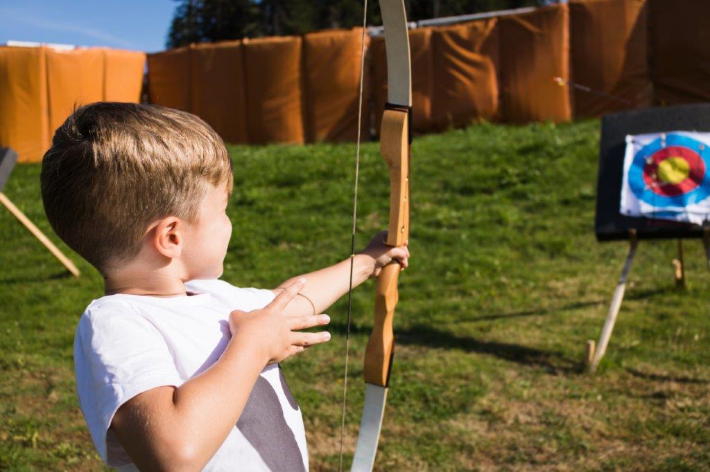 Abbildung eines Jungen, der mit Pfeil und Bogen auf Zielscheibe zielt