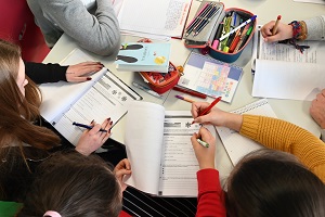 Zu sehen sind Schülerinnen und Schüler die gemeinsam Arbeitshefte bearbeiten.